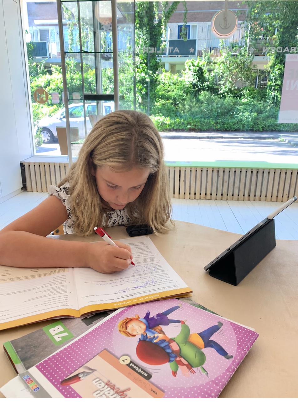 Een meisje oefent geconcentreerd opgaven voor de doorstroomtoets aan de werktafel bij JJED-Educatie.