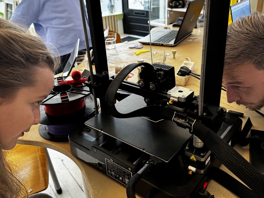 Een leerling en een vakdocent bekijken samen van dichtbij hoe de 3D-printer werkt.