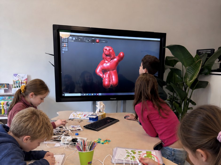 Kinderen werken aan de grote tafel; op het digibord staat een 3D-ontwerp.