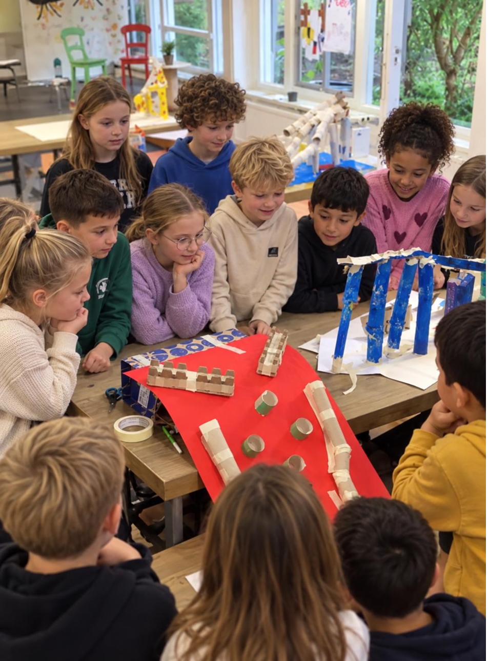 Kinderen bekijken samen elkaars zelfgebouwde constructies tijdens de uitvinderswerkplaats